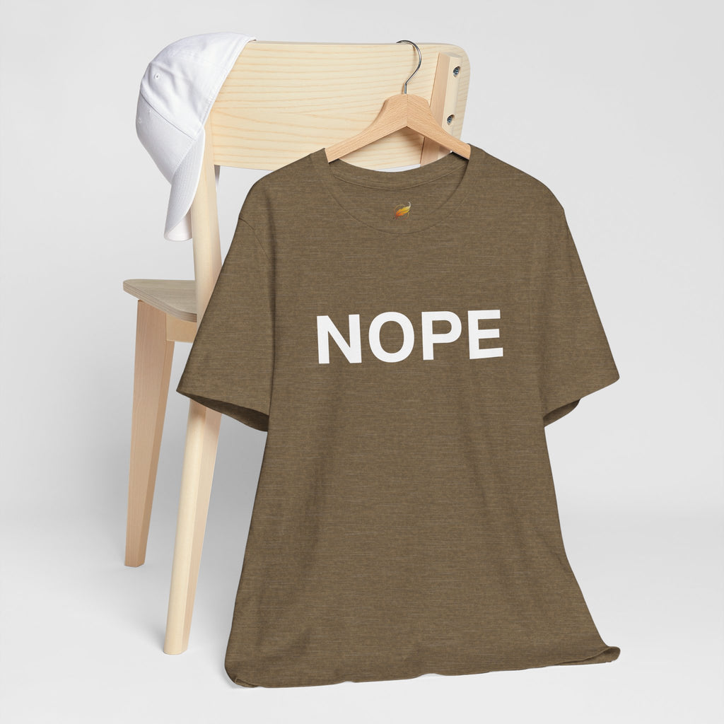 A heather olive crew neck t-shirt with 'NOPE' in bold white lettering across the chest on a wooden hanger and hung from the back of a wooden chair with a white hat also hanging from the chair. Shown against a plain white background.
