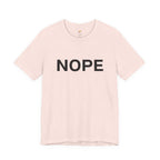 A soft pink short-sleeve crewneck t-shirt with the word 'NOPE' printed in bold black capital letters across the chest, displayed on a clean white background.